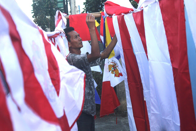 Wawan (32) merapikan bendera dagangannya di Jalan Ahmad Yani, Kota Bandung, Selasa(02/08/2016). (Jurnalpos/Pandu Muslim)
