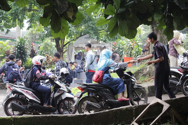 Mahasiswi memberikan kartu parkir pada satpam di parkiran gedung FISIP UIN Bandung, Selasa (01/11/16). (Jurnalpos/Desianti Yus Rusana)