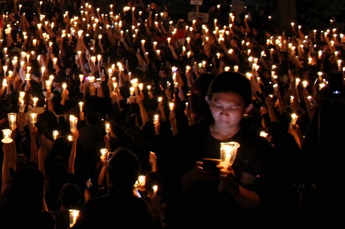 Julia (45) menyalakan lilin bersama ribuan masa di depan Gedung Sate, Jalan Diponegoro, Kota Bandung, Sabtu (13/5/2017). Aksi ini diselenggarakan sebagai bentuk menuntut ditegakannya keadilan dan kedamaian di Indonesia. (Reival/Magang)