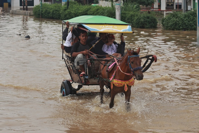 Sejumlah warga melintasi kawasan banjir menggunakan delman di Jalan Anggadireja Baleendah, Kabupaten Bandung, Selasa (14/11/2017). Delman merupakan kendaaran alternatif banjir ketika jalan tidak bisa dilalui oleh kendaraan umum lainnya. (Reival Akbar/Jurnalposmedia)